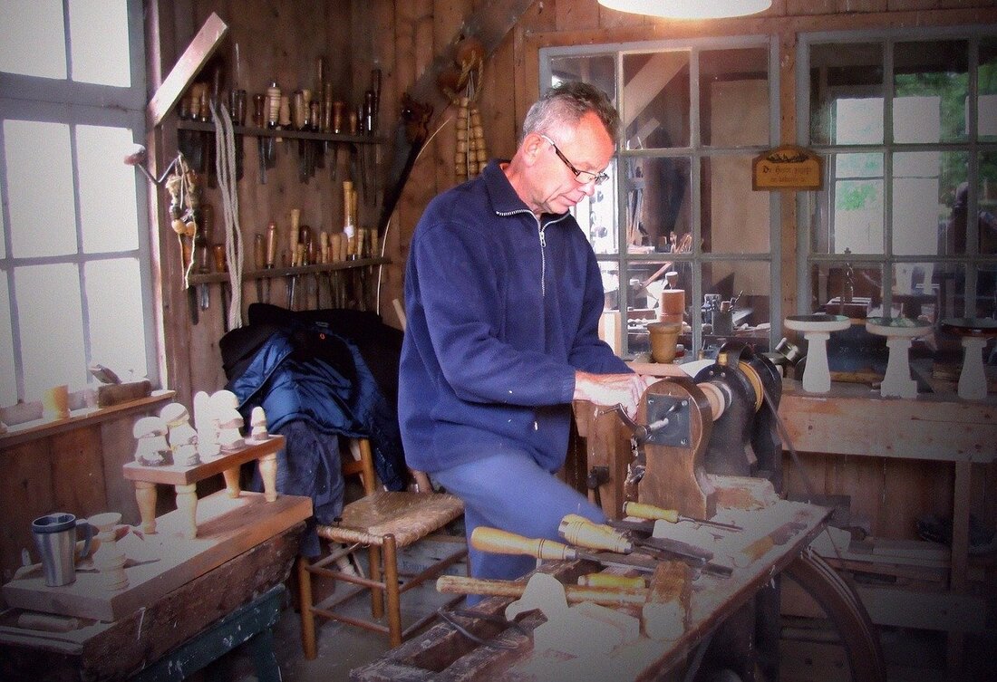 Cabinet maker at work on a lathe among traditional hand tools in a joinery workshop