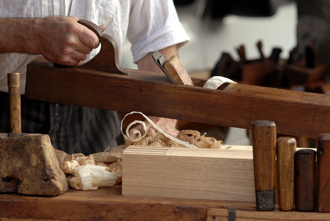 c14758_joiner-nottingham_orig Craftsman using a traditional wood plane to finish a joinery piece, with wood shavings on the workbench
